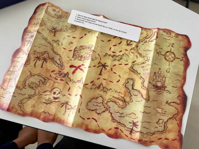 Zerknitterte Schatzkarte mit Inseln, Palmen, Totenkopf und Schatztruhe, teilweise von einer Notiz bedeckt.